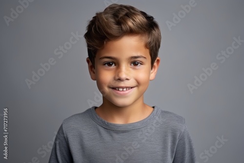 Portrait of a cute little boy looking at camera and smiling, over grey background