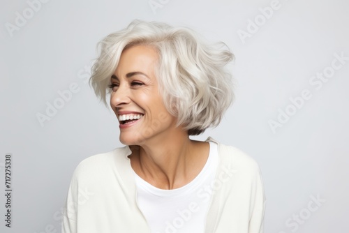 Portrait of a happy senior woman with white hair over grey background