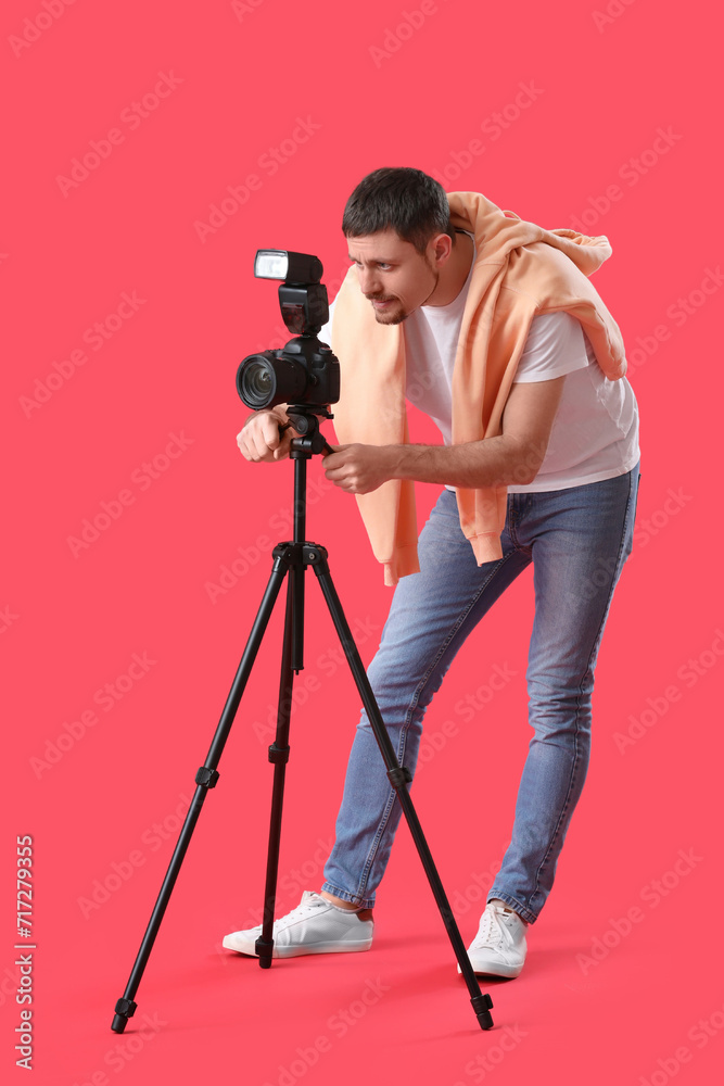 Male photographer with professional camera on red background