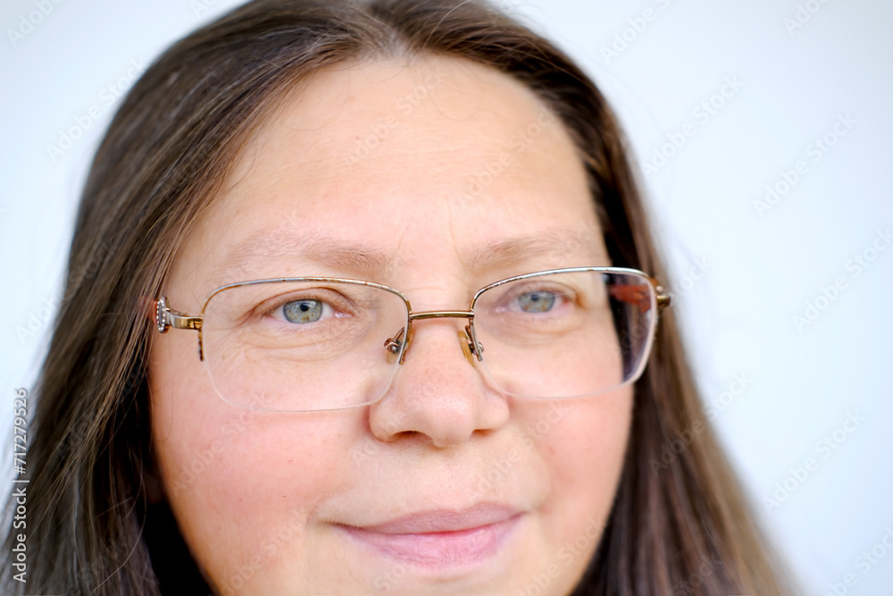 close-up female face of elderly woman 50 years old with long hair in glasses, on lips slight smile of maturity, inner strength resilience, mature appearance and graceful wisdom, knowledge, experiences close-up female face of elderly woman 50 years old with long hair in glasses, on lips slight smile of maturity, inner strength resilience, mature appearance and graceful wisdom, knowledge, experiences