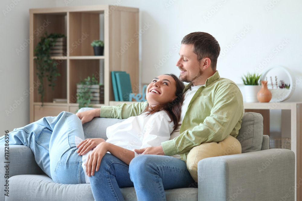 Happy young couple resting on sofa at home