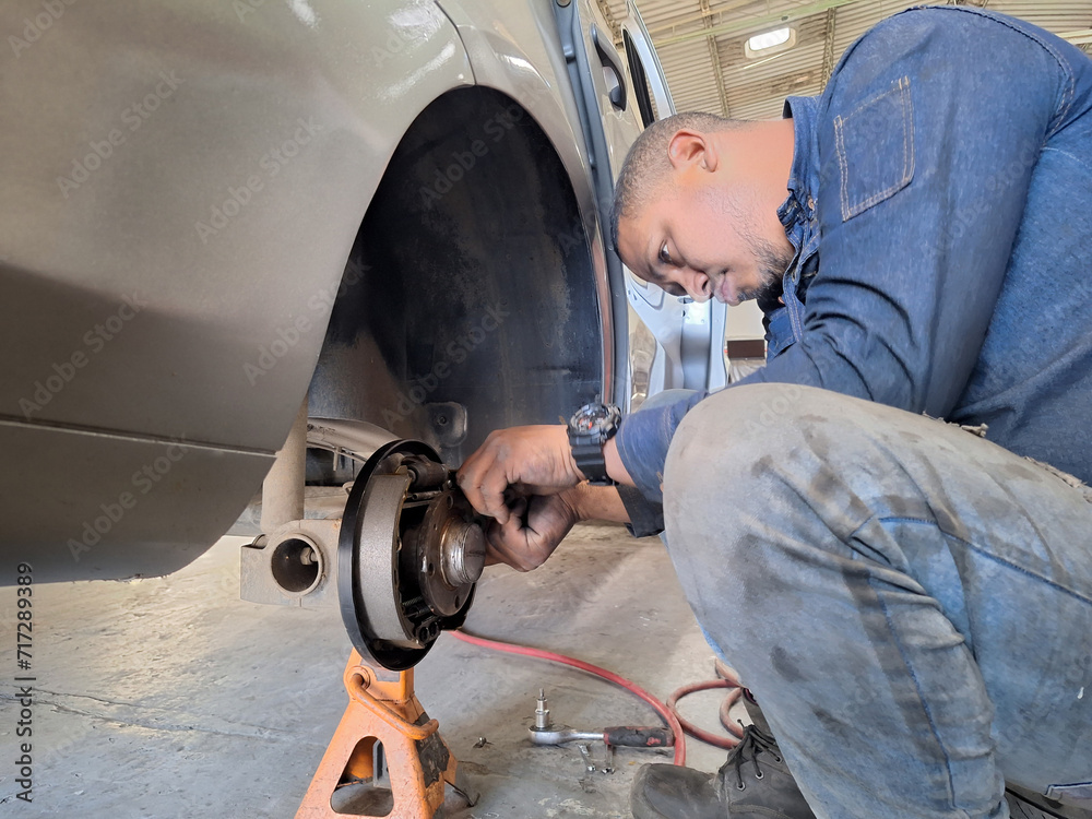 a black mechanic repairing the rear brake of a car