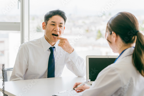 口内炎を医師に相談するアジア人のビジネスマン（口腔ケア・口角炎・口唇ヘルペス）
 photo
