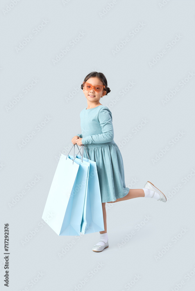 Cute little girl with shopping bags on light background Cute little girl with shopping bags on light background