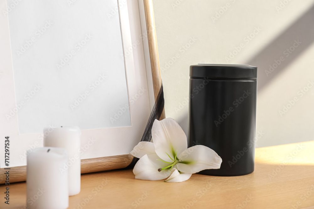 Mortuary urn, candles and lily flower on wooden table, closeup Mortuary urn, candles and lily flower on wooden table, closeup