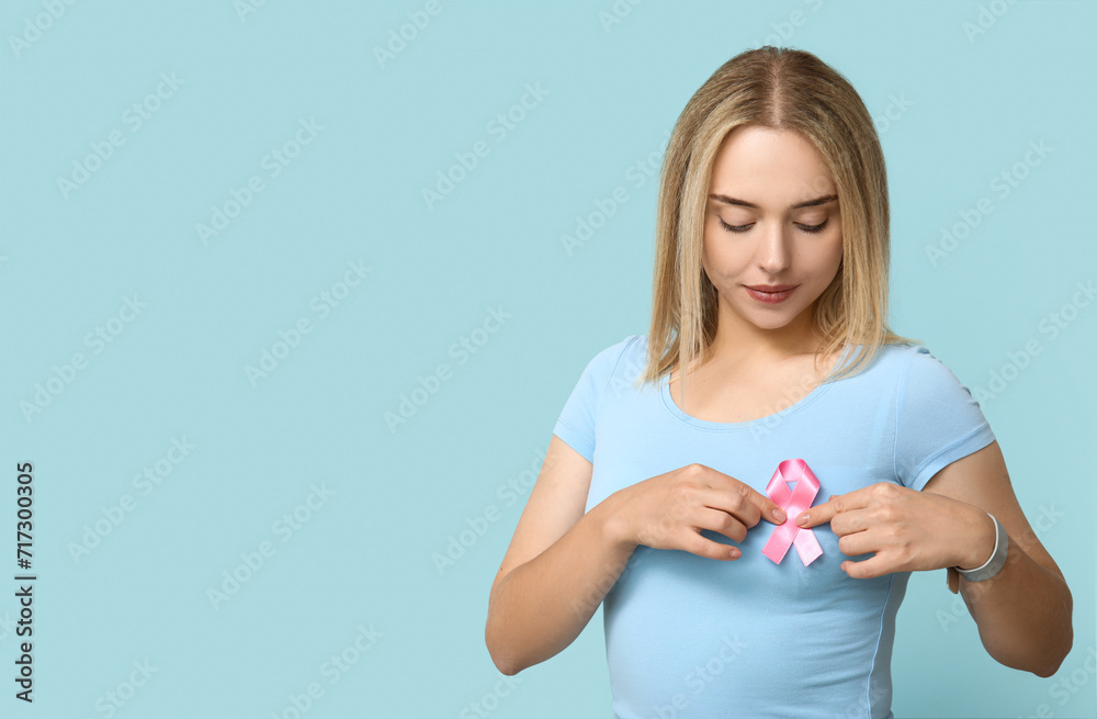 Young woman with pink ribbon on blue background. Breast cancer awareness concept Young woman with pink ribbon on blue background. Breast cancer awareness concept