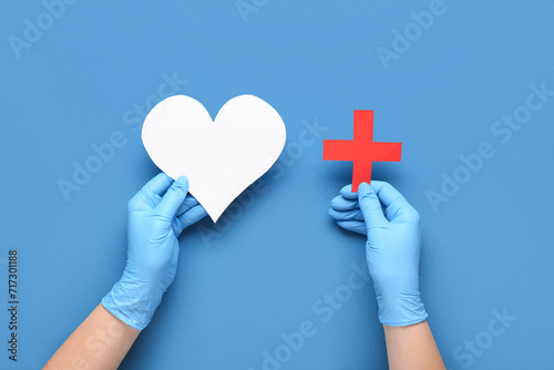 Fototapeta Naklejka Na Ścianę i Meble -  Doctor with paper heart and cross on blue background