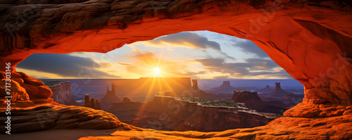 A panoramic view of a sunrise framed by the iconic Mesa Arch in Canyonlands National Park
