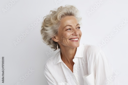 Smiling senior woman looking at camera. Portrait of beautiful mature woman in white shirt.