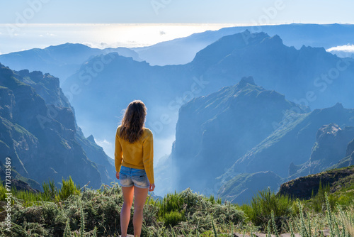 Female tourist enjoys picturesque view from the summit of a volcanic island on a sunny summer day. Pico do Arieiro, Madeira Island, Portugal, Europe.