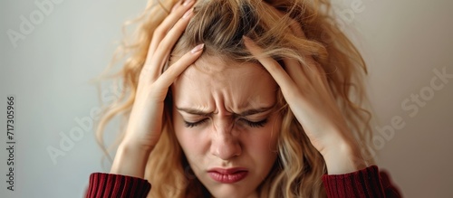 Stressed young blonde woman desperate and in pain with hands on head, suffering from headache and migraine.