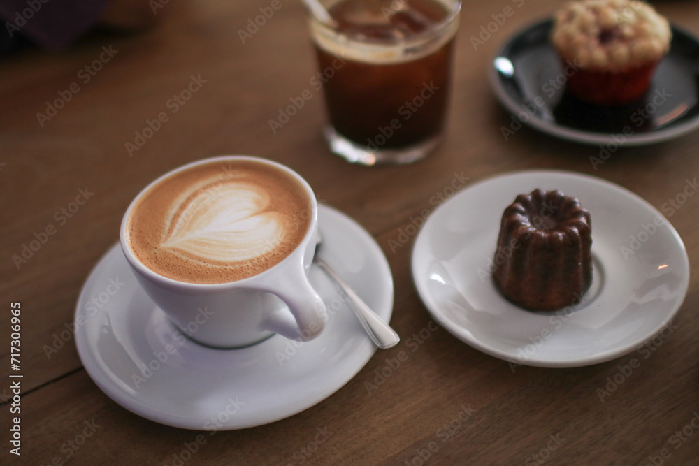 Hot Latte espresso coffee with heart shape latte art in white ceramic cup serve with bakery on wooden table. Morning breakfast. Hot Latte espresso coffee with heart shape latte art in white ceramic cup serve with bakery on wooden table. Morning breakfast.