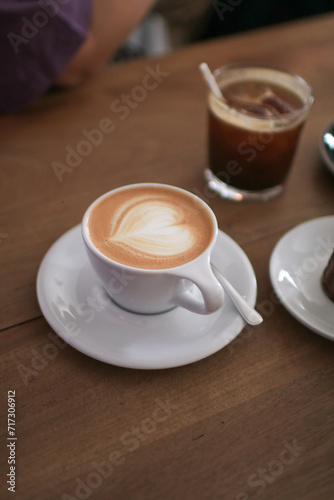 Hot Latte espresso coffee with heart shape latte art in white ceramic cup serve with bakery on wooden table. Morning breakfast.