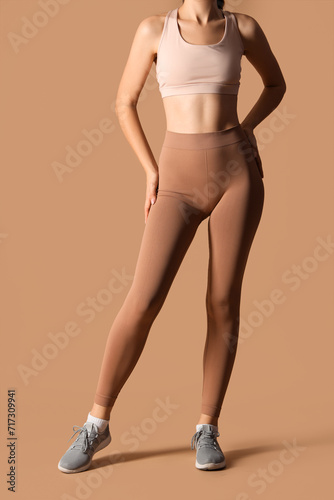 Fotografija Sporty young woman in leggings on beige background