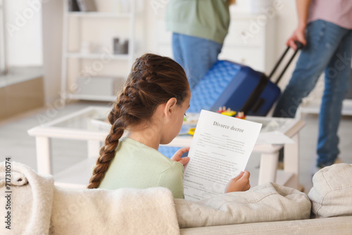 Sad little girl with divorce decree at home photo