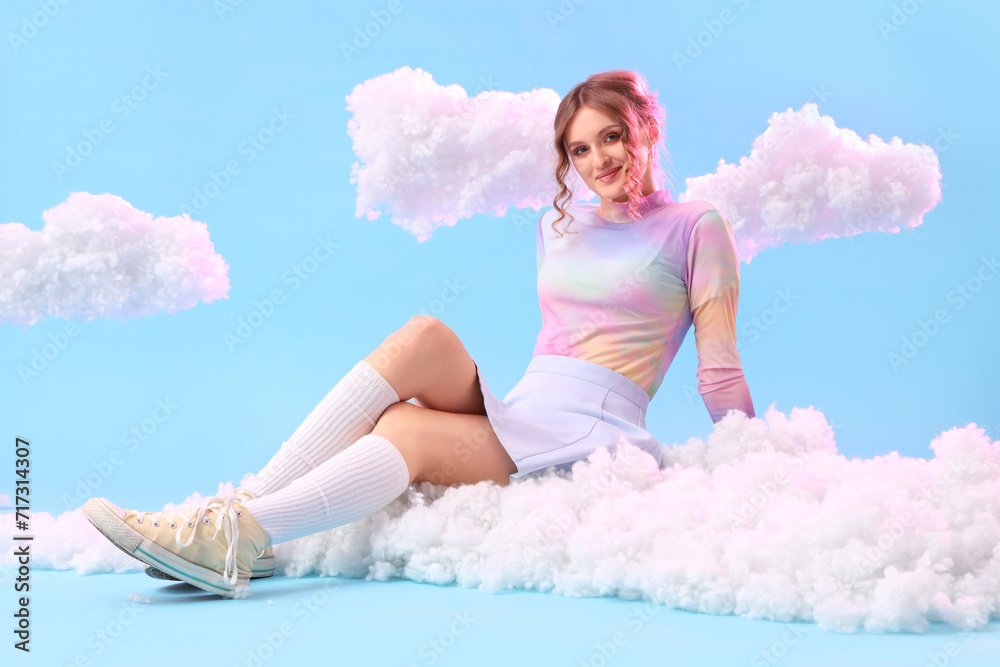 Young woman with white clouds sitting on blue background Young woman with white clouds sitting on blue background
