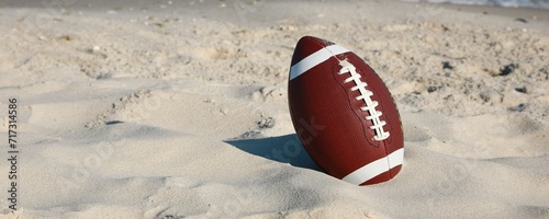 American football ball on beach. Space for text