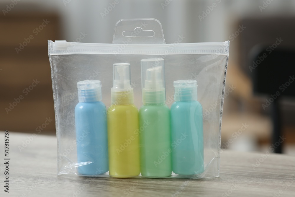Cosmetic travel kit in plastic bag on wooden table, closeup. Bath accessories Cosmetic travel kit in plastic bag on wooden table, closeup. Bath accessories