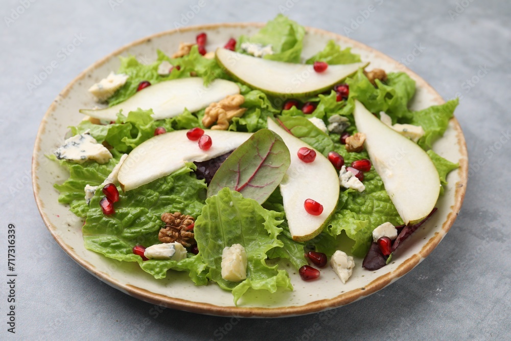 Plate with delicious pear salad on grey textured table, closeup