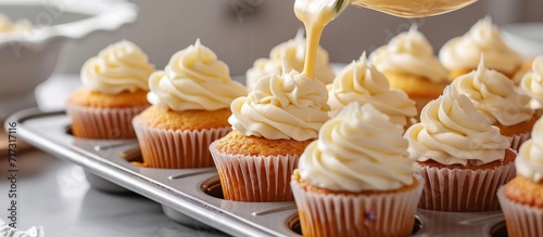 Pouring cupcake batter into cupcake pan with liners to bake vanilla cupcakes.