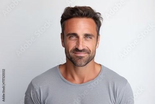 Portrait of a handsome mature man smiling and looking at camera while standing against grey background