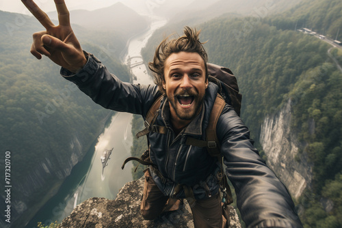 At the edge of a cliff, a guy takes a daring selfie with a breathtaking mountainous landscape as the backdrop, showcasing both adventure and serenity.