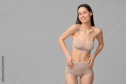Beautiful young woman in beige underwear on white background