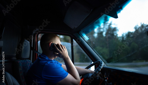 male truck driver is driving a truck and talking on the phone. ​