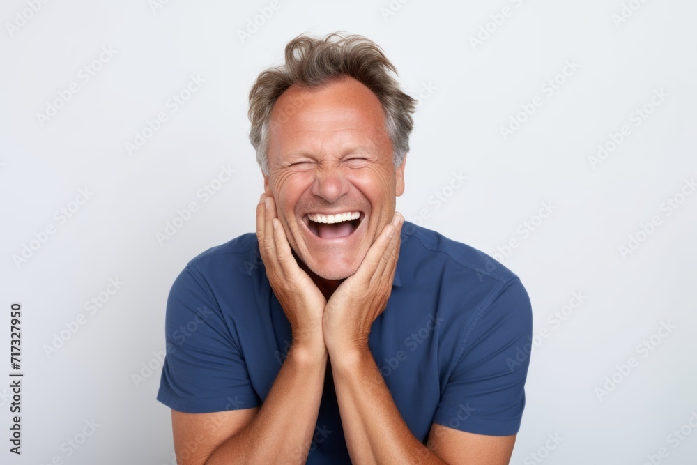 Portrait of happy senior man laughing and looking at camera against grey background Portrait of happy senior man laughing and looking at camera against grey background