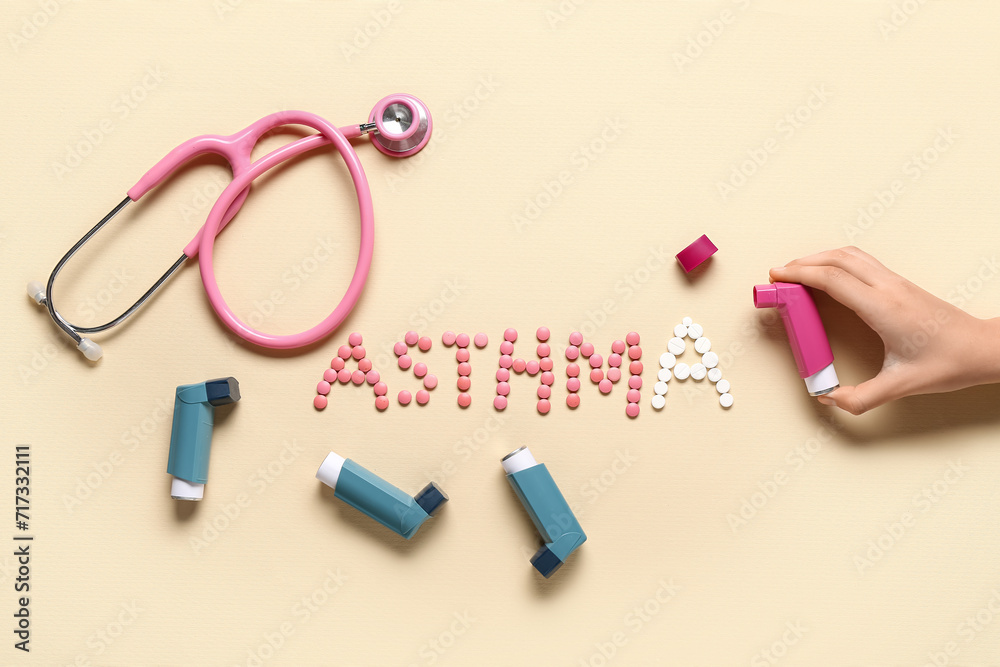 Child's hand with inhaler, stethoscope and word ASTHMA made of pills on beige background Child's hand with inhaler, stethoscope and word ASTHMA made of pills on beige background
