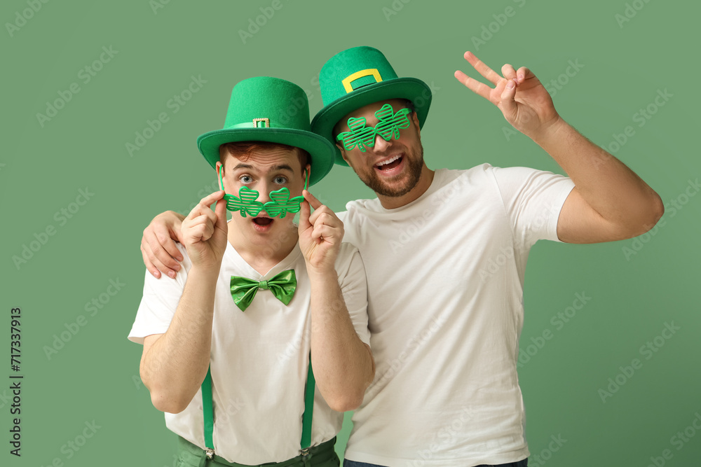 Happy young men with leprechaun's hats and party glasses on green background. St. Patrick's Day celebration Happy young men with leprechaun's hats and party glasses on green background. St. Patrick's Day celebration