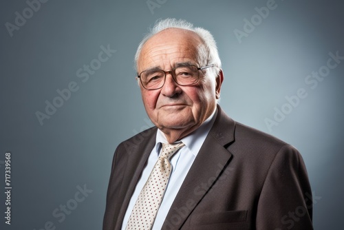 Elderly business man with glasses and a suit on a gray background