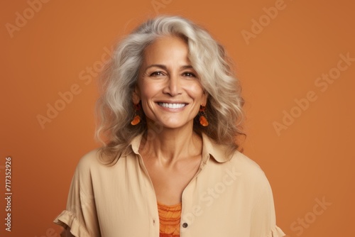 Portrait of a happy senior woman looking at camera over orange background