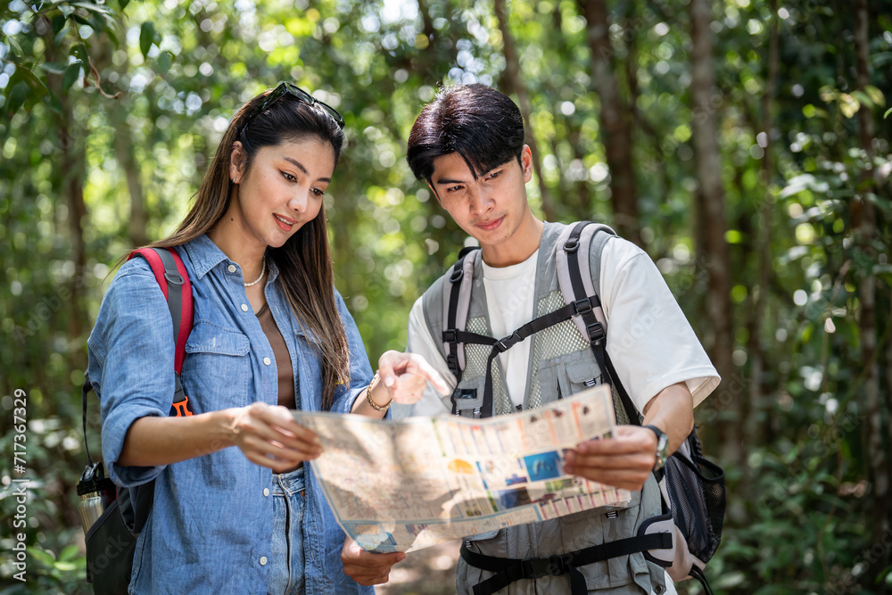 Asian young man and woman backpacker tourist travel in forest wild. 