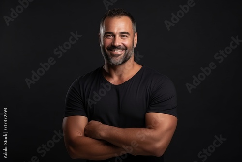 Portrait of a smiling mature man with arms crossed against black background