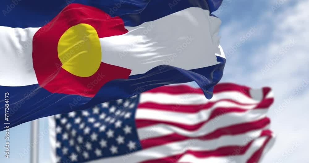 Colorado and US flags waving in the wind on a clear day