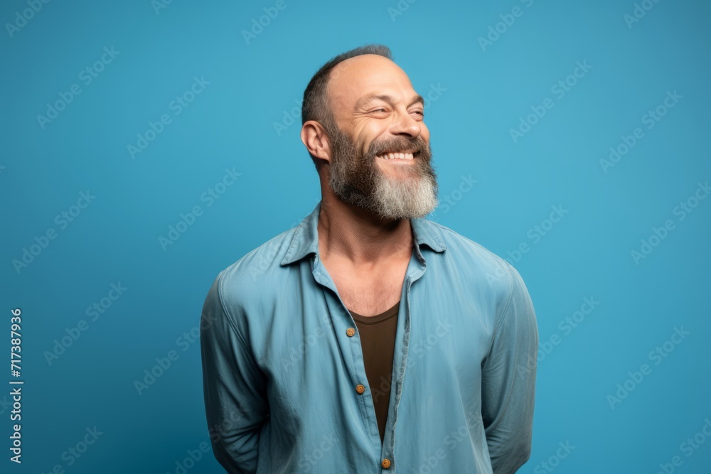 Happy senior man with beard and mustache laughing and looking up on blue background Happy senior man with beard and mustache laughing and looking up on blue background