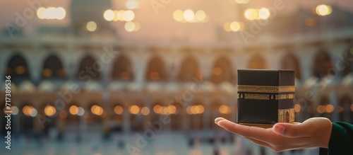 muslim hand holding miniature kaaba with mosque background. banner illustration for tawaf, Umrah or Hajj agency advertisement
