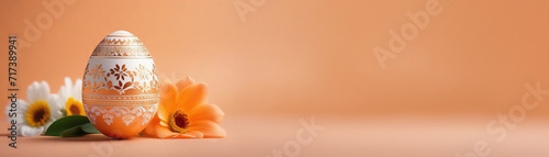 Banner with an Easter egg decorated with an openwork pattern on a peach background with flowers and space for your advertisement. Easter concept