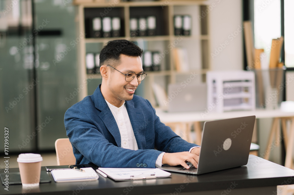 Young attractive man using laptop and tablet while sitting at her working place. Concentrated at work. Young attractive man using laptop and tablet while sitting at her working place. Concentrated at work.