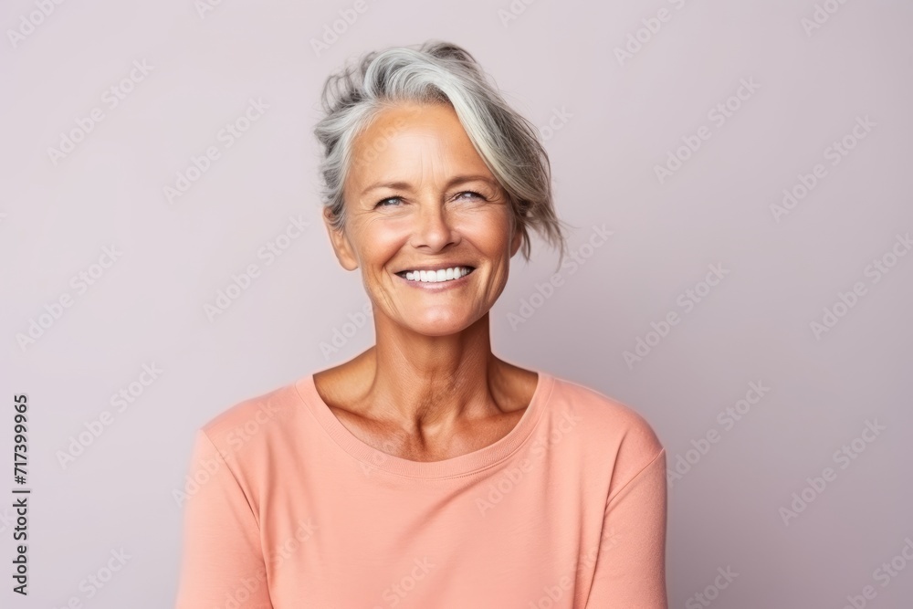 Portrait of a happy senior woman smiling at the camera against grey background Portrait of a happy senior woman smiling at the camera against grey background