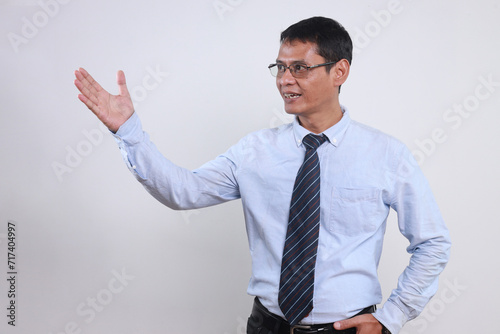 Adult Asian male in shirt and tie raising hand presenting copy space for text or ads