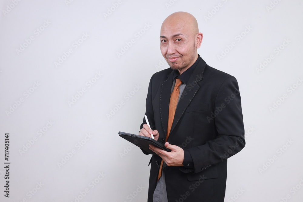 Cheerful young adult Asian business man working on digital tablet and looking at camera isolate on white background Cheerful young adult Asian business man working on digital tablet and looking at camera isolate on white background