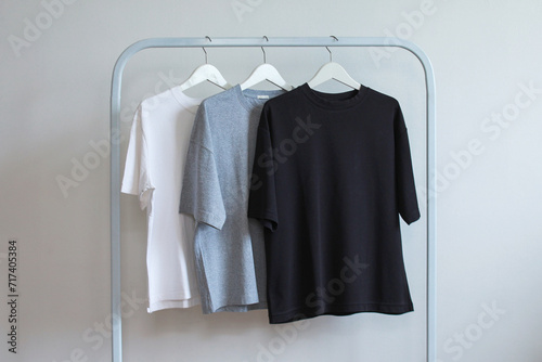 Row collection of black, gray and white color t-shirts hanging on clothes hanger in clothing rack over white background
