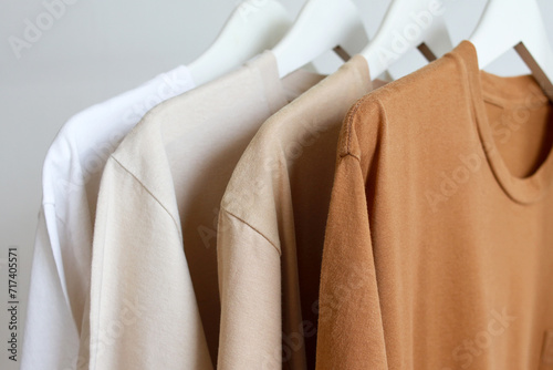 Row of brown t-shirts colors variant hanging on white hanger on rack clothes photo