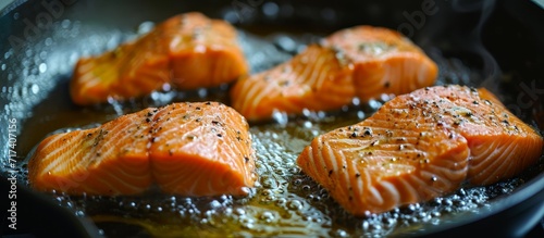 Salmon pieces sizzling on a stovetop with oil.
