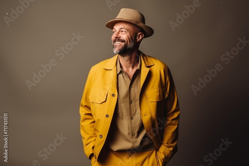 Portrait of a smiling middle-aged man in a yellow jacket and hat.