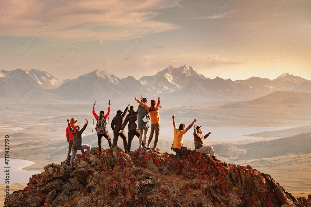 Big group of happy tourists are having fun and greeting sunset at mountain top. Active vacations concept - obrazy, fototapety, plakaty 