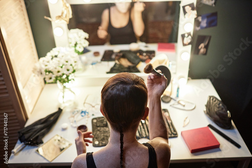 High angle view at unrecognizable performer doing makeup by vanity mirror backstage in theater or circus