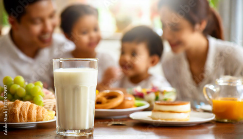 Happy family having breakfast at home. Focus on the glass of milk